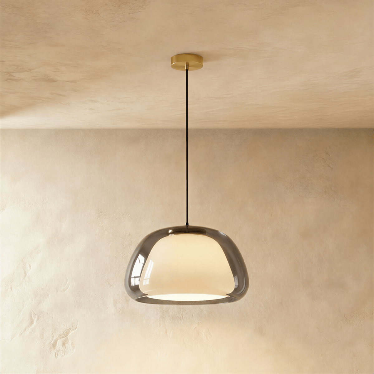 Clérachic larger pendant light in smoked grey glass over a glowing opal inner shade, brass canopy and cord against limewash.