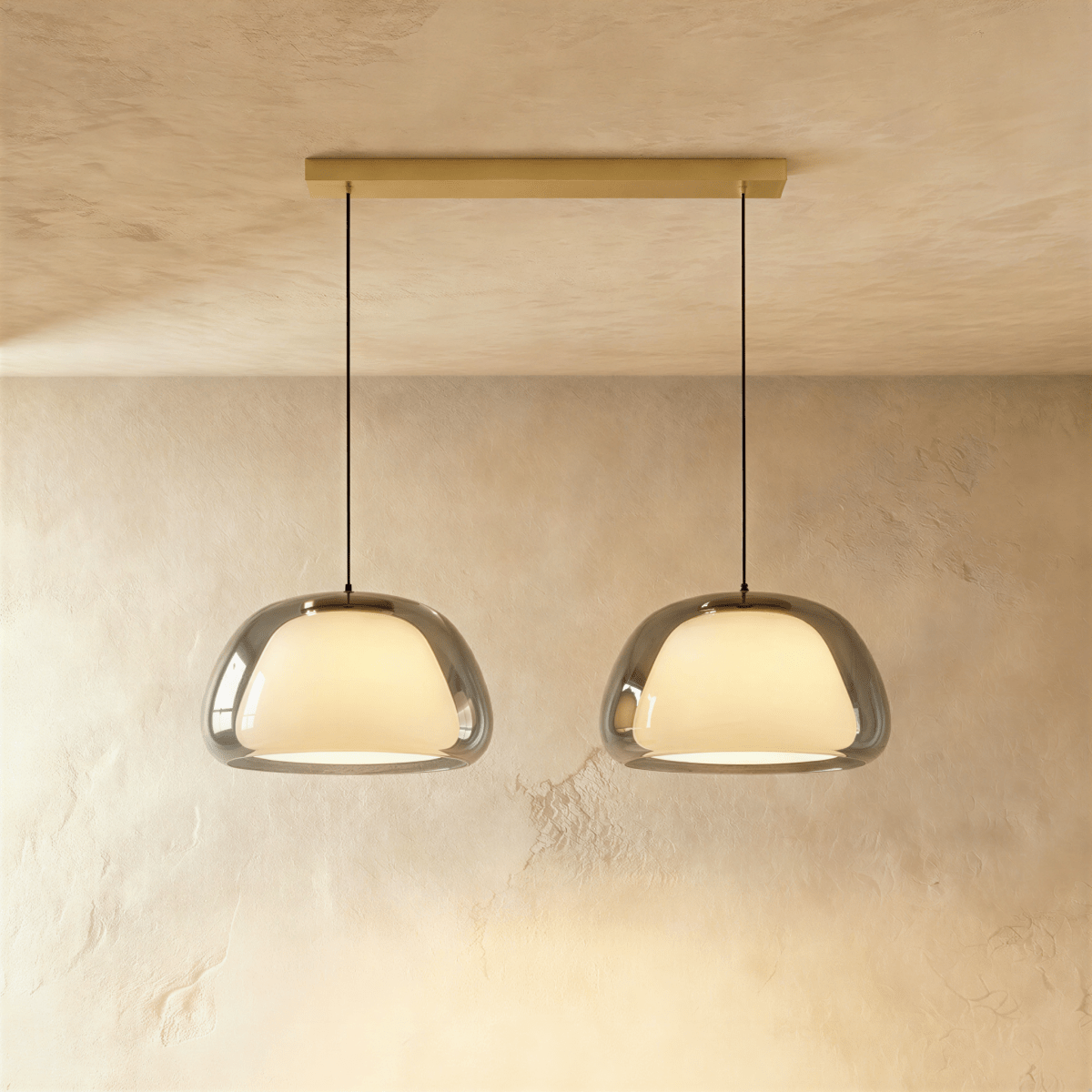 Clérachic two-head pendant light in smoked grey glass with opal diffusers, hung from a brass bar canopy on black cords.