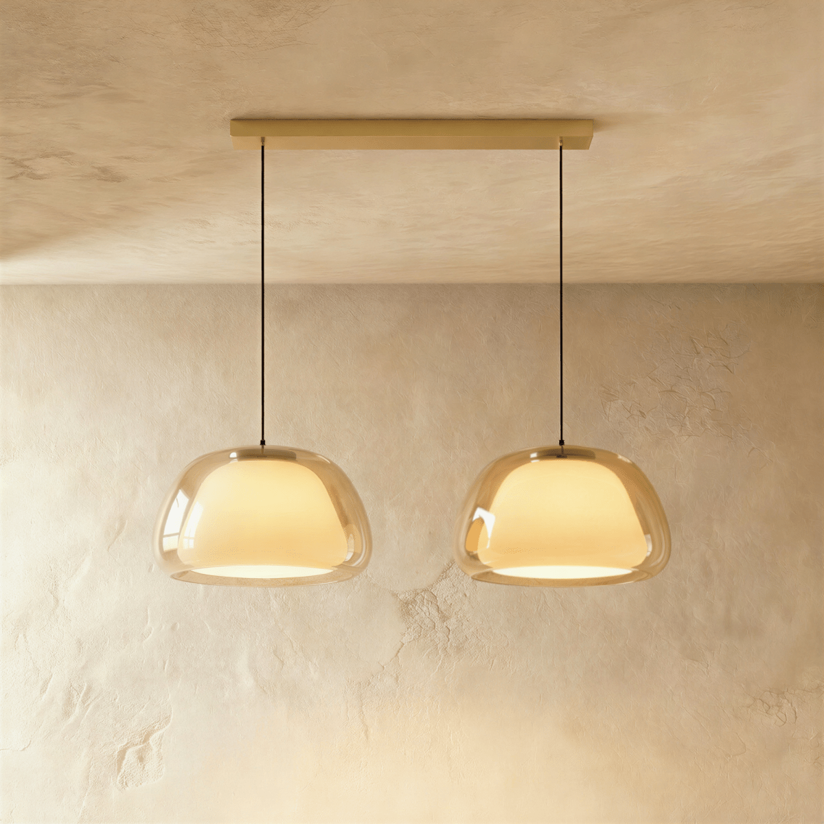 Clérachic two-head pendant light in amber glass with glowing opal diffusers, hanging from a slim brass bar canopy.