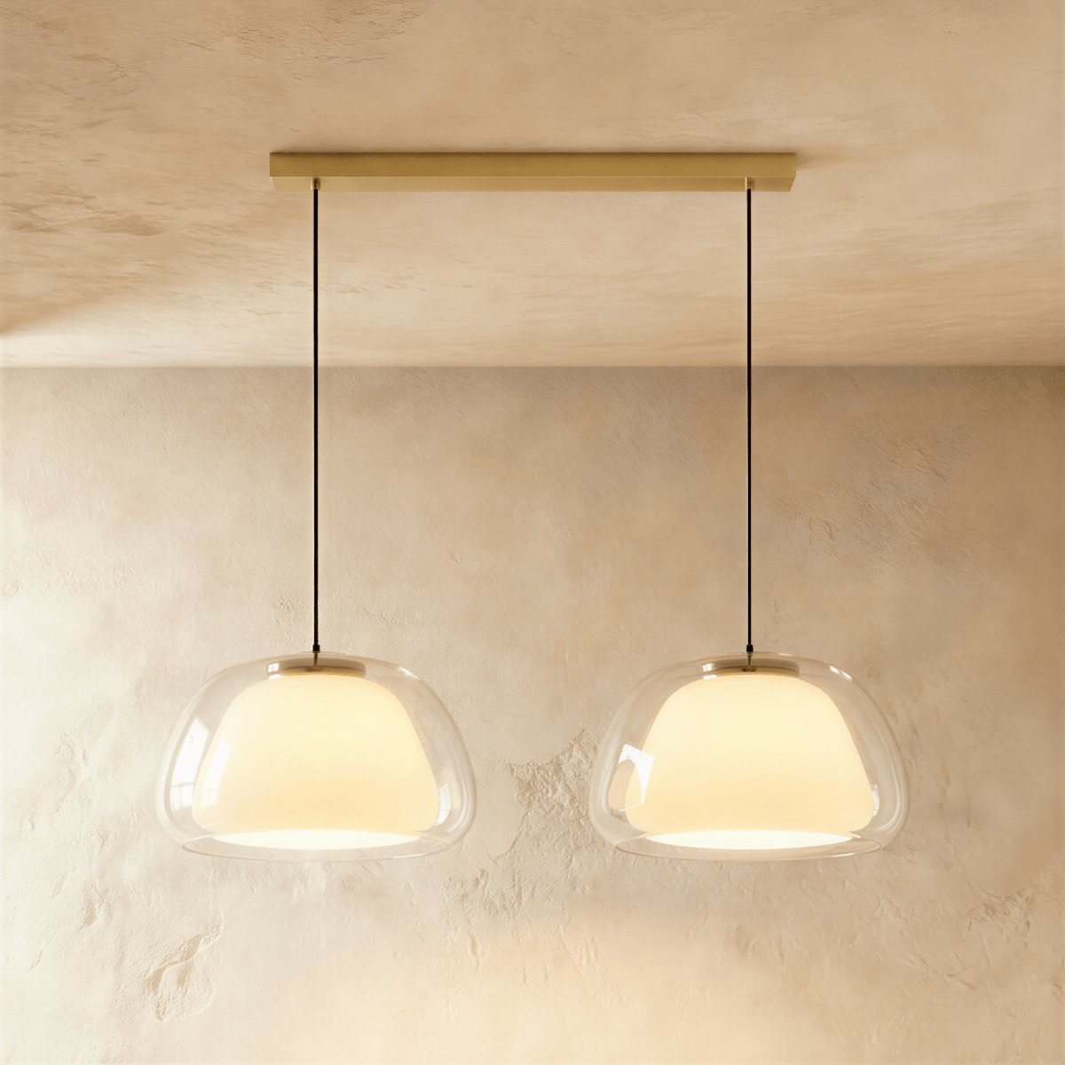 Clérachic two-head pendant light with larger clear glass shades and opal diffusers, hung from a long brass bar canopy.