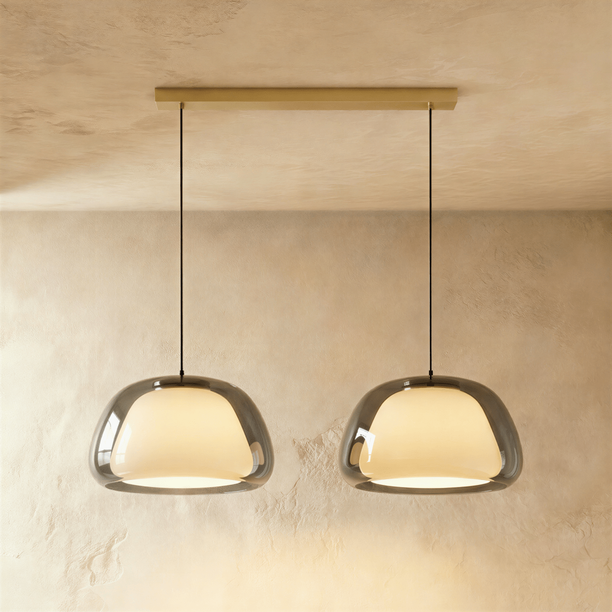 Clérachic two-head pendant light with larger smoked grey glass shades over opal diffusers, on a long brass bar canopy.