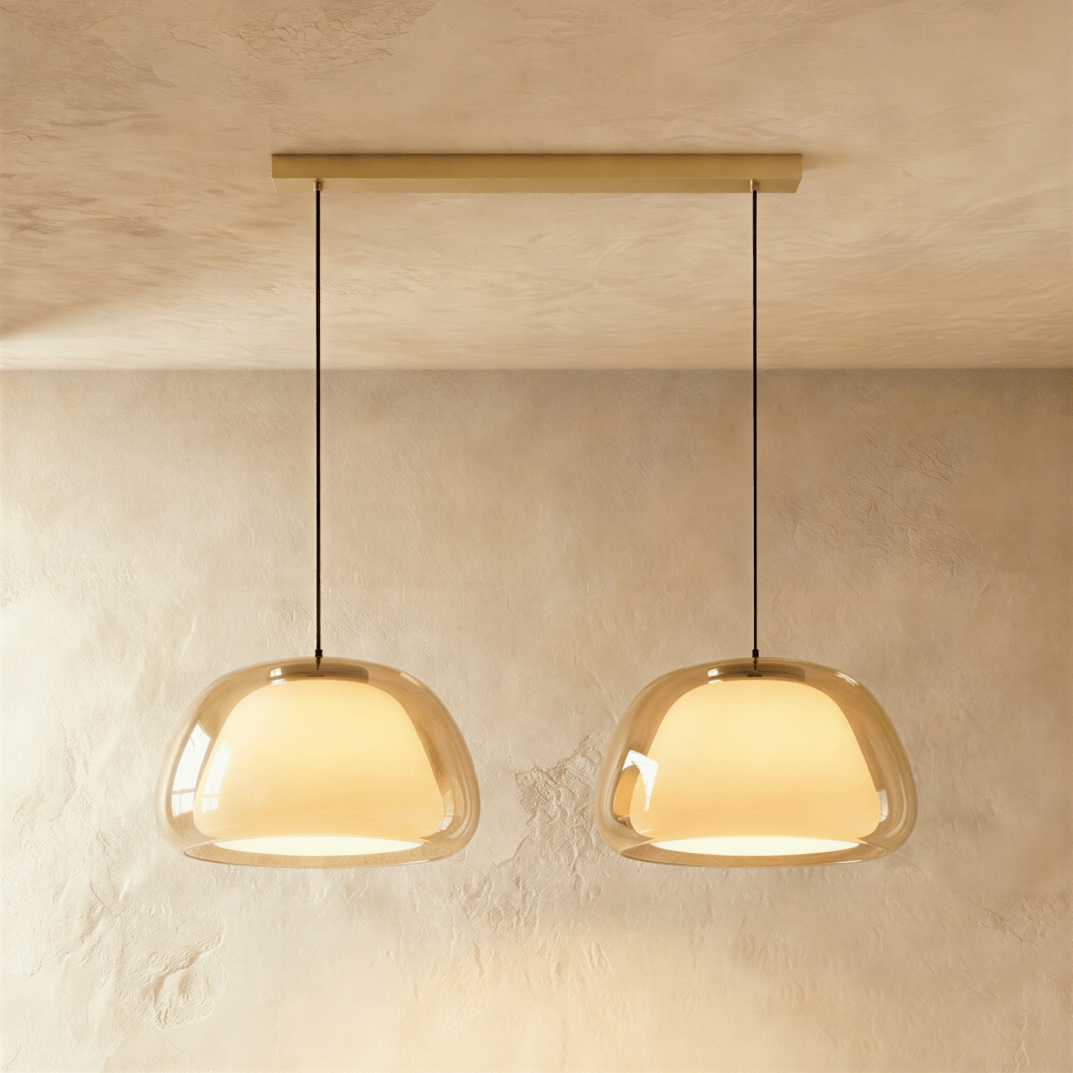 Clérachic two-head pendant light with larger amber glass shades over glowing opal diffusers, on a long brass bar canopy.