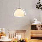 Clérachic clear glass pendant light with an opal inner shade hanging above a wooden dining table set with cups and fruit.