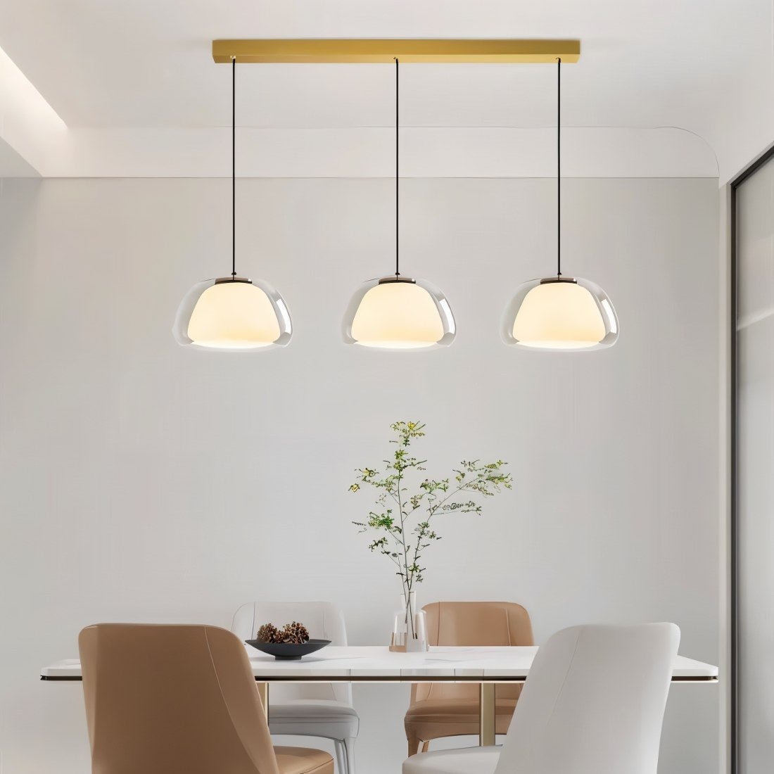 Clérachic three-head pendant light in clear glass with opal diffusers above a marble dining table with tan and white chairs.