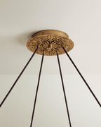 Clérachic chandelier ceiling canopy in aged gold with pierced scrollwork and four dark fabric cords descending from it.