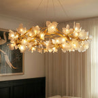 Clérachic chandelier lit from below, warm bulbs glowing within frosted glass petals on gold branches in a living room.