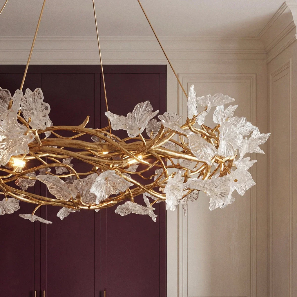 Clérachic chandelier branches and clear glass petals seen from below against plum cabinetry and cream panelled walls.
