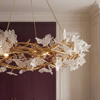 Clérachic chandelier branches and clear glass petals seen from below against plum cabinetry and cream panelled walls.