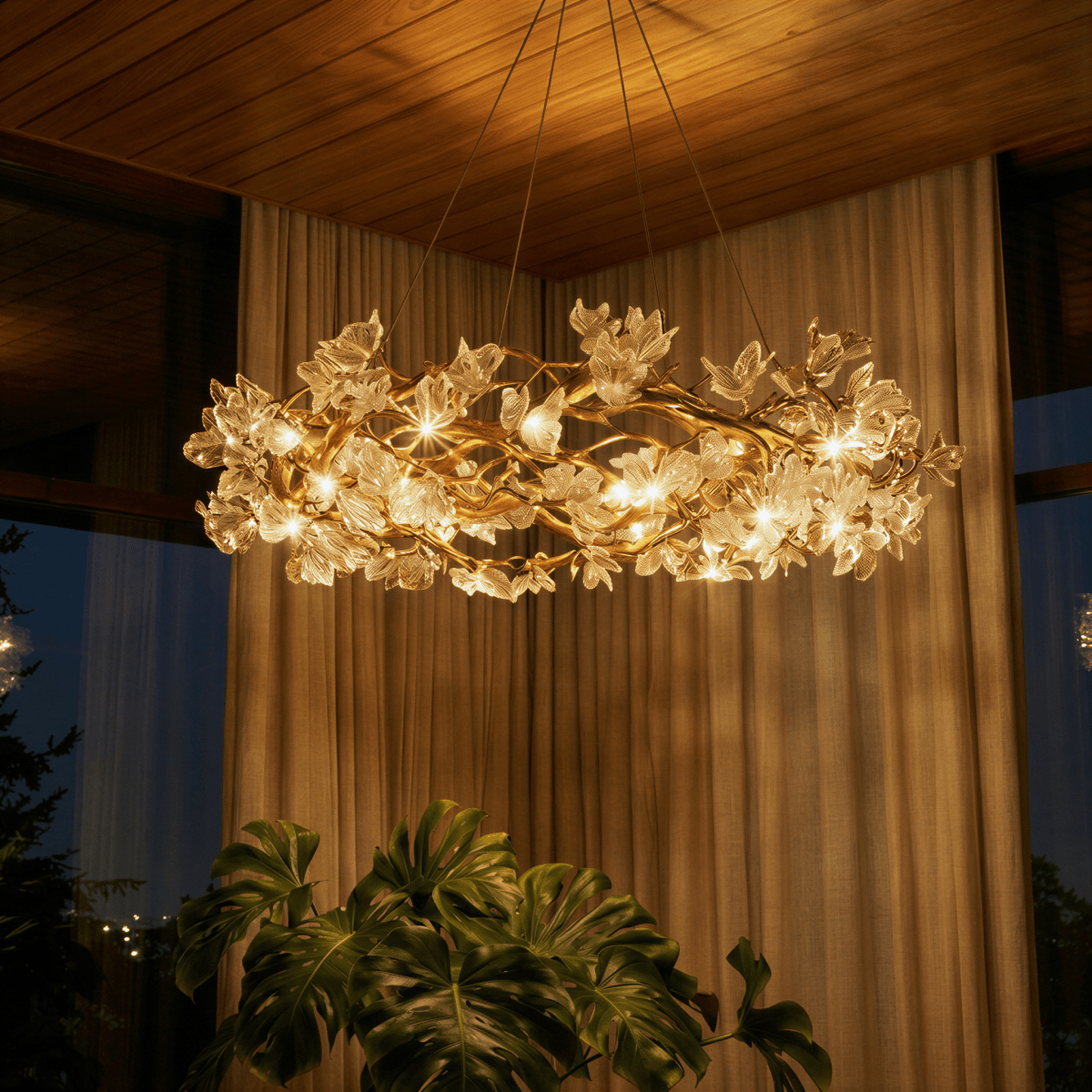 Clérachic chandelier at dusk, its bulbs lit warm through glass petals beneath a timber ceiling and linen curtains.