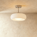 Clérachic semi-flush pendant with a rounded white glass shade on a short brushed chrome stem, softly lit against limewash.