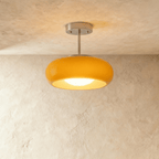 Clérachic semi-flush pendant with a rounded yellow glass shade and glowing opal bulb cover on a brushed chrome stem.