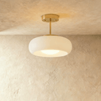 Clérachic semi-flush pendant with a rounded white glass shade on a short brass stem and round brass canopy, softly lit.