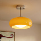Close view of a Clérachic yellow glass pendant on a chrome stem, showing the glossy shade and the glowing opal bulb below.
