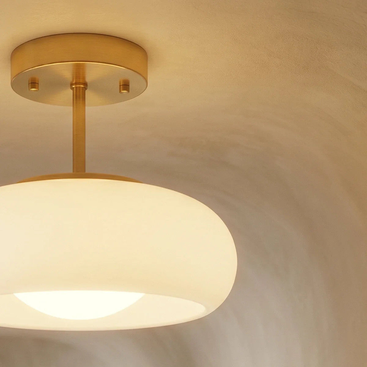 Close view of a Clérachic white glass pendant, showing its round brass canopy, slim stem and glowing opal bulb cover.