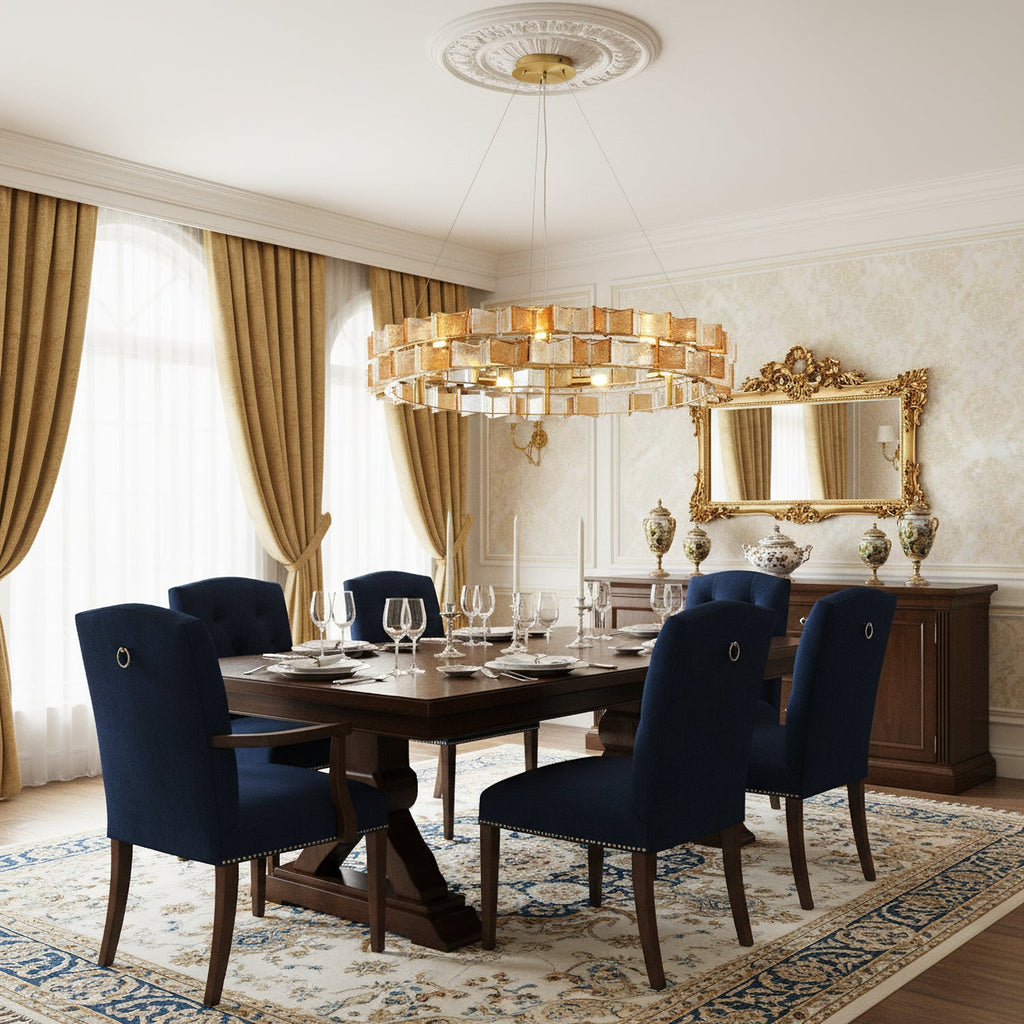 Above a dark wood dining table with navy chairs, this amber Clérachic chandelier sits in a room with gold curtains and an ornate mirror.