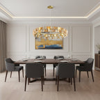 In a modern dining room with pale panelled walls and grey chairs, an amber Clérachic chandelier hangs low over a long wooden table.