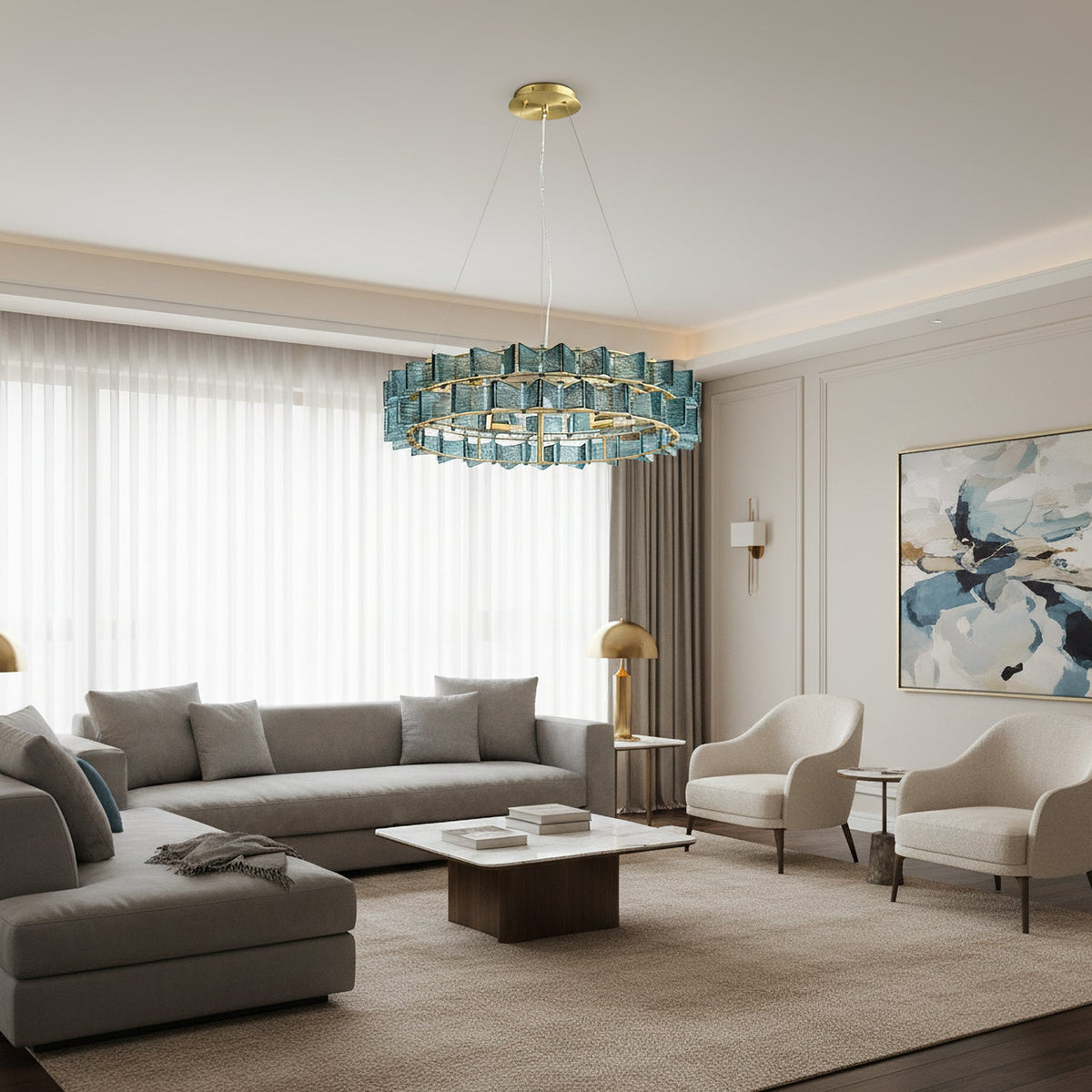 A blue Clérachic chandelier hangs in a bright grey living room with a corner sofa, a white coffee table and sheer curtains.
