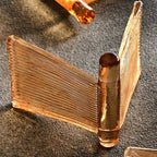 Single amber glass piece from this Clérachic chandelier on a grey surface, its ribbed folds meeting at a thick glass post.
