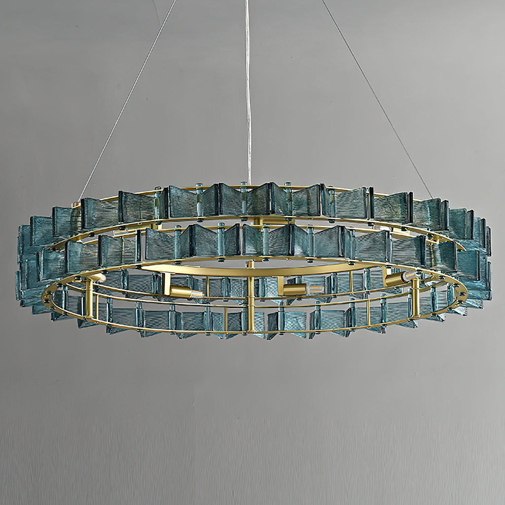 Straight-on view of a blue Clérachic chandelier on a grey backdrop, two tiers of ribbed glass around a brass ring with its bulbs visible.