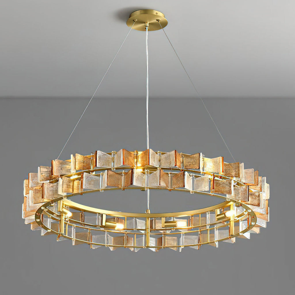 An amber Clérachic chandelier lit on a grey backdrop, the brass canopy and thin suspension wires above the ring of ribbed glass.
