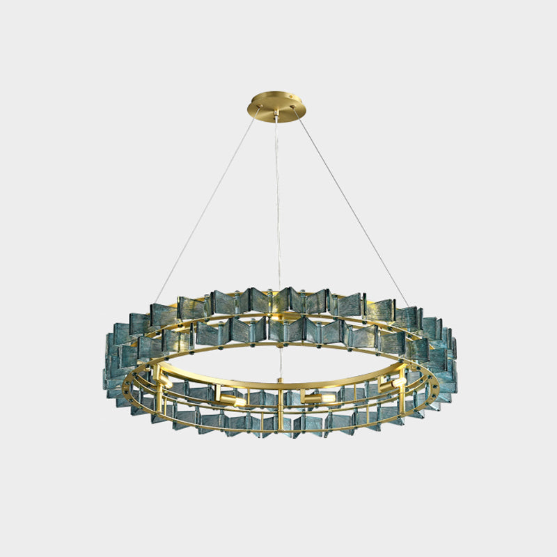 This Clérachic chandelier in blue glass on a light grey backdrop, hung from a gold canopy over a brass ring.