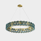 A close crop of a blue Clérachic chandelier on light grey, its ring of ribbed glass with bulbs glowing inside.