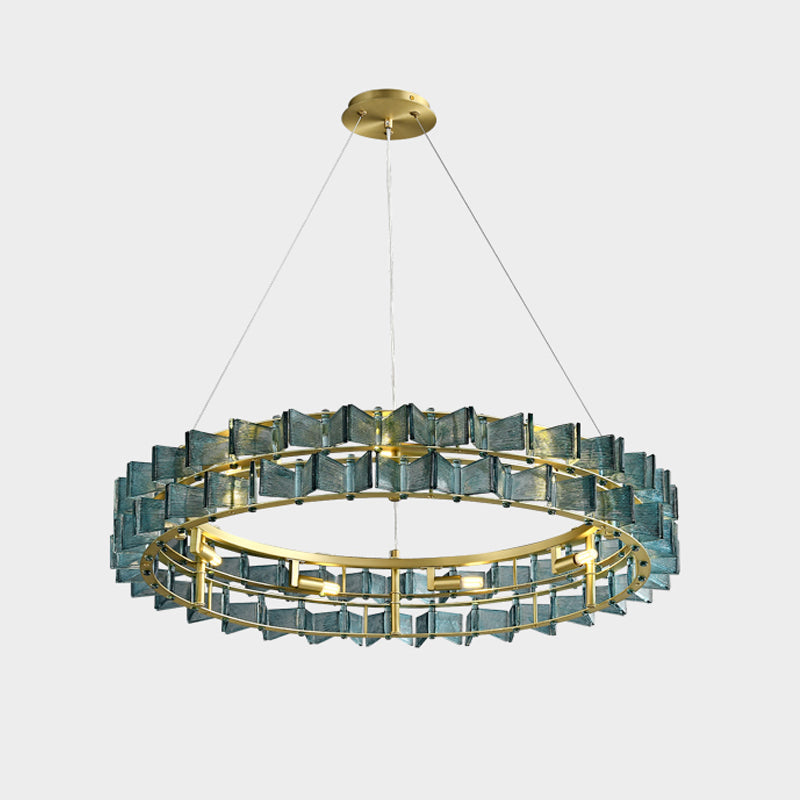 A close crop of a blue Clérachic chandelier on light grey, its ring of ribbed glass with bulbs glowing inside.