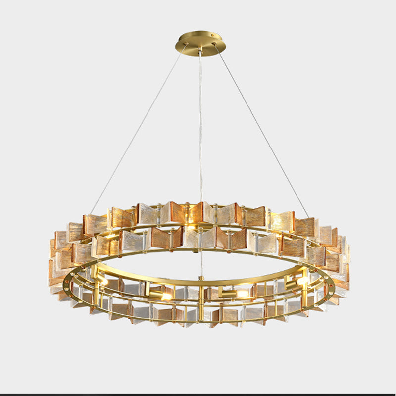 Amber and clear glass blades alternate around the brass ring of this Clérachic chandelier on a light grey backdrop.
