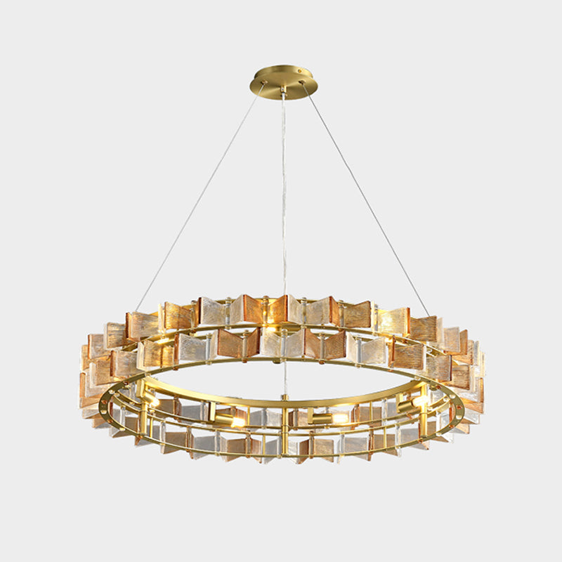A Clérachic chandelier in amber on light grey, hung from a gold canopy, its bulbs lit inside the ring of ribbed glass.