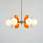 Clérachic chandelier with opal globes and glowing orange acrylic petals fanned out from a chrome hub