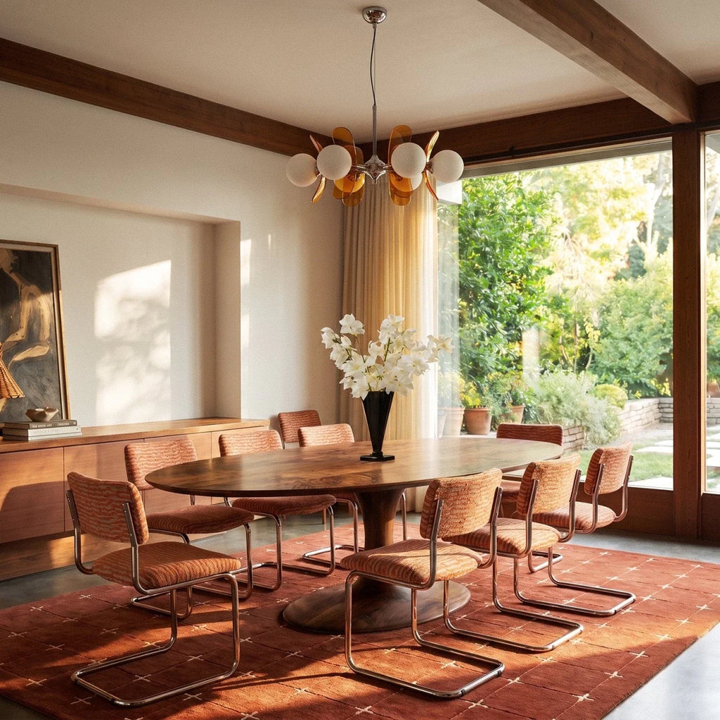 Clérachic orange petal chandelier above an oval walnut dining table, beside a glazed garden door