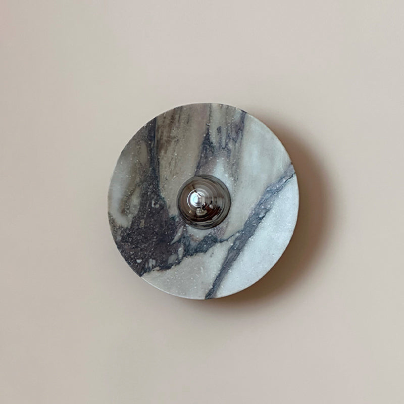 Straight-on view of the same grey Clérachic marble wall light, its vein sweeping to the right of the polished chrome dome.