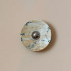 Golden veining and green-black marks cross the white stone of this Clérachic marble wall light, with a chrome dome at its centre.