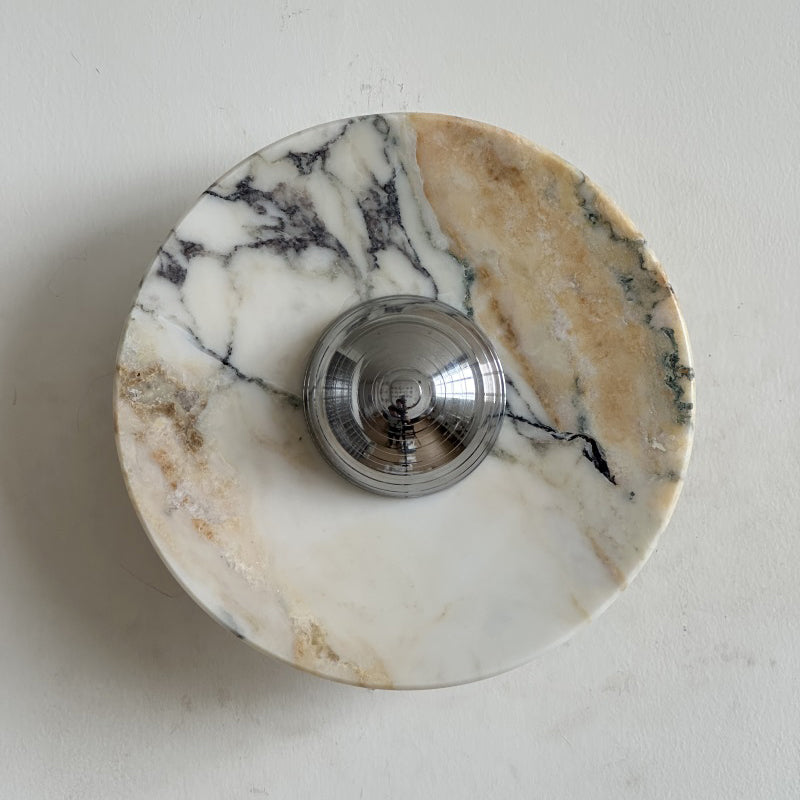 Across this Clérachic marble wall light runs a bold gold band with purple-black veining, around a chrome dome in the middle.