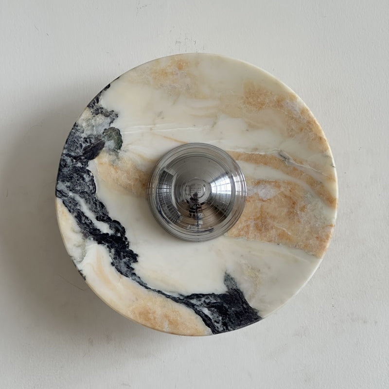 Front view of the Clérachic marble wall light in cream stone with a broad black vein that sweeps across the lower half.