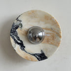 Front view of the Clérachic marble wall light in cream stone with a broad black vein that sweeps across the lower half.