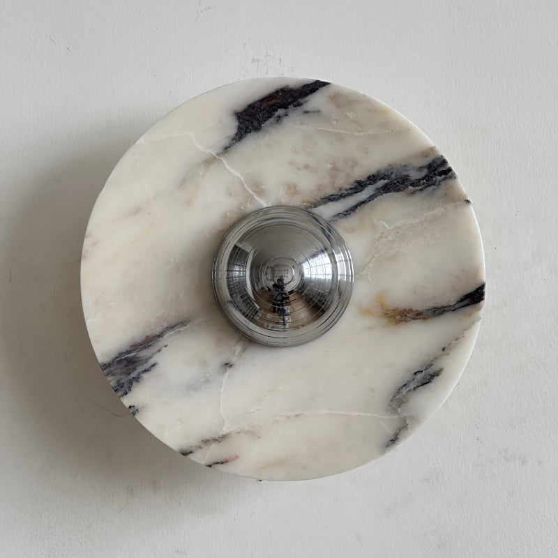 A Clérachic marble wall light in cream stone with sharp black veins running from the upper right into the chrome dome.