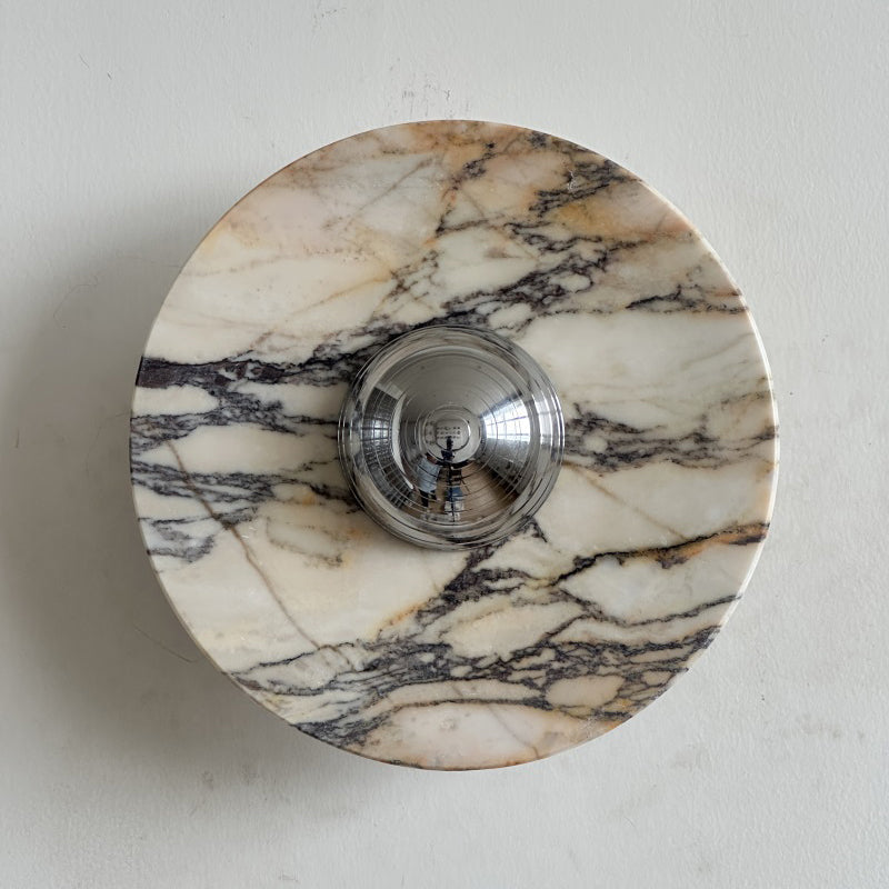 One dark vein climbs from lower left to upper right across the pale grey-white stone of this Clérachic marble wall light.