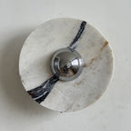 A thick dark vein runs down the right side of this Clérachic marble wall light, with brown flecks near its chrome centre.