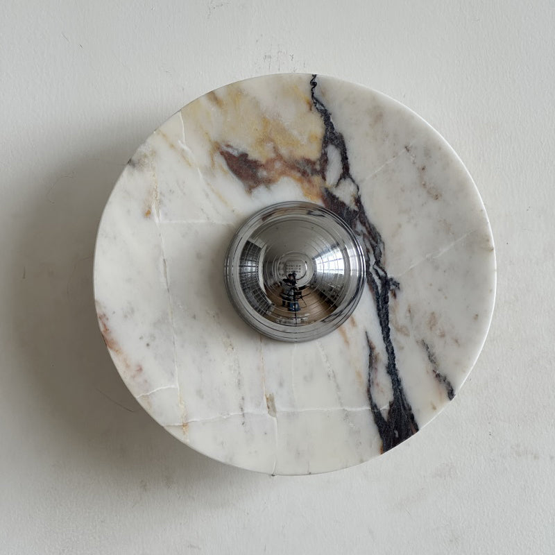 A Clérachic marble wall light in white stone with a dark purple vein falling down the right side, and brown flecks near the centre.
