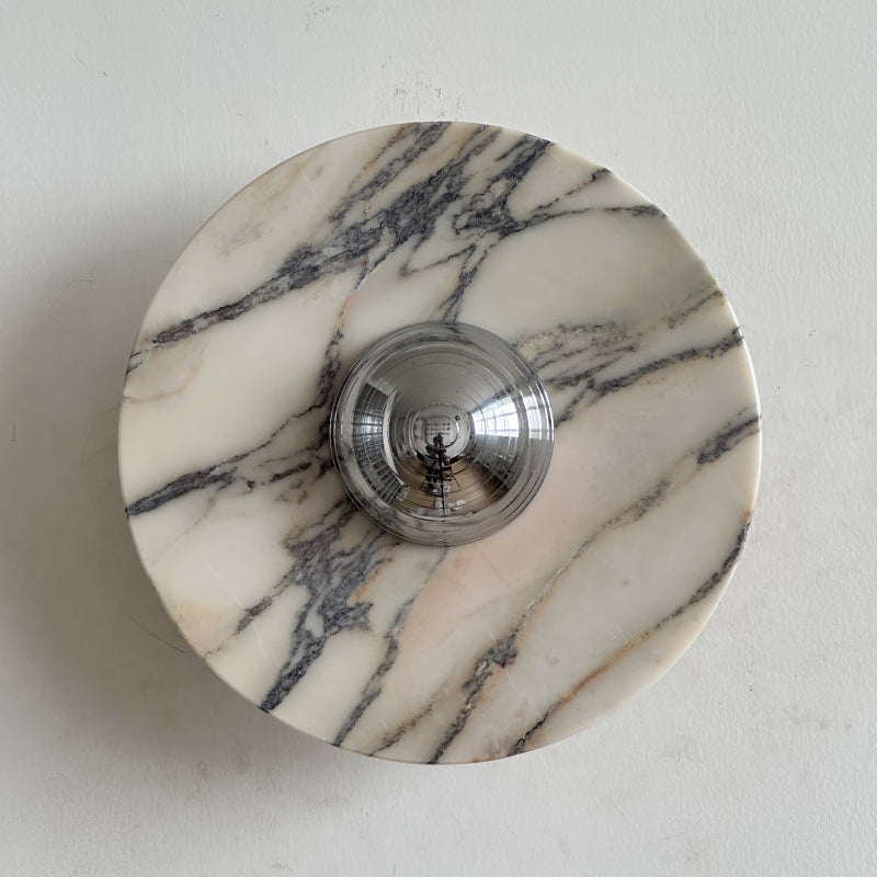 A Clérachic marble wall light with dense, fine black veining on a creamy disc, and a polished chrome dome in the centre.