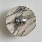 A Clérachic marble wall light with dense, fine black veining on a creamy disc, and a polished chrome dome in the centre.