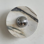 A Clérachic marble wall light with a long dark vein across the upper right and pale pink-grey stone around the chrome dome.