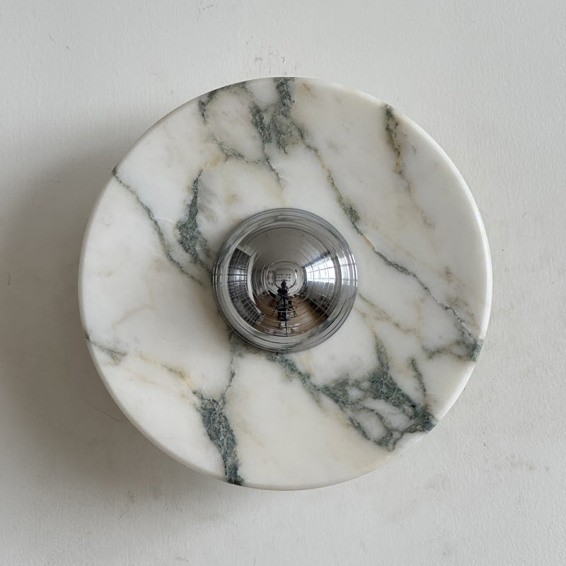 A Clérachic marble wall light with soft green-grey veins across white stone and a few brown lines, with a chrome dome at the centre.
