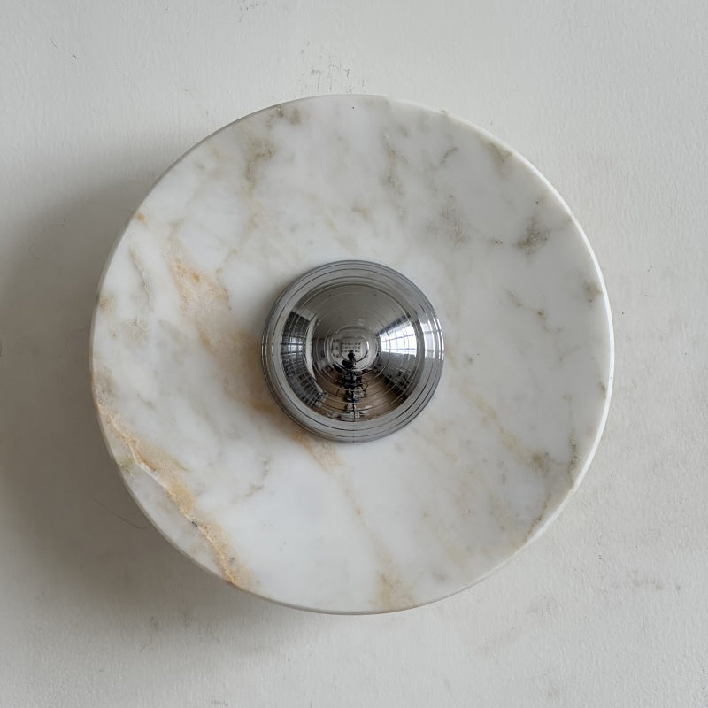 A Clérachic marble wall light in clean white stone with soft gold and grey veins, its chrome dome catching the light.