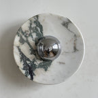 A Clérachic marble wall light with green-grey and brown veins running down the left side of a white disc, around a chrome dome.