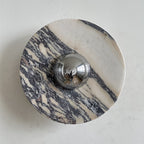 A Clérachic marble wall light with broad purple-grey bands slanting across a pale disc, with a chrome dome at its middle.