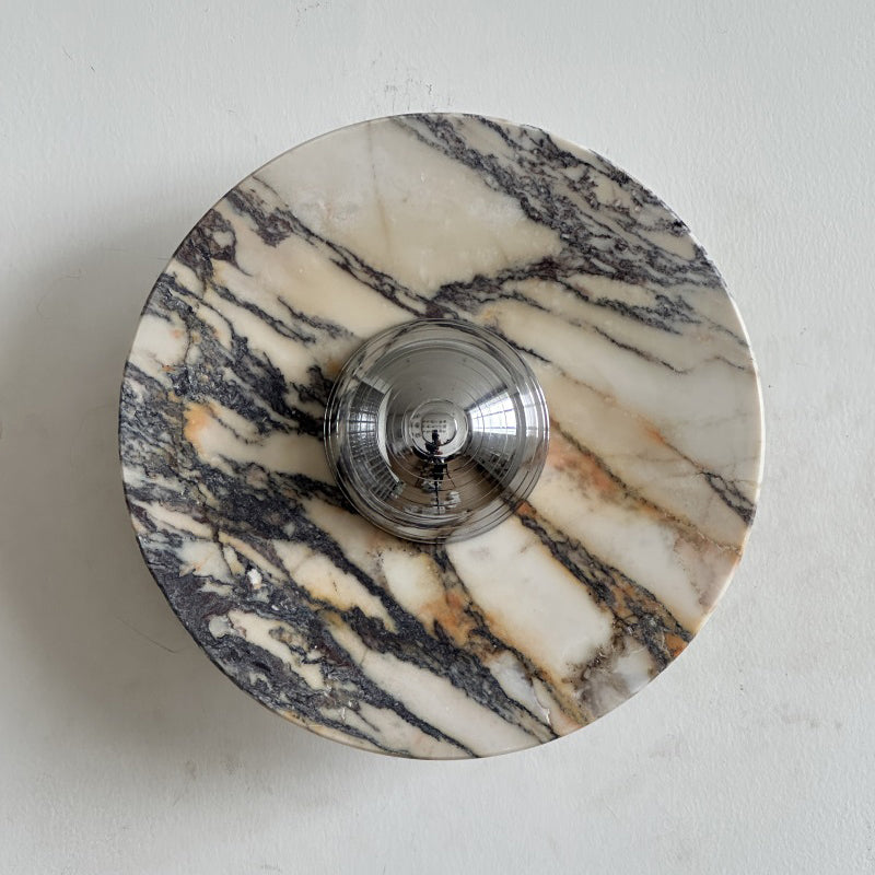 A Clérachic marble wall light with dense purple-grey and gold veins across a cream disc, around a chrome dome.