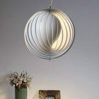 The Clérachic Round Metal Pendant Light hangs above a green vase of pink flowers, warm light between white slats.