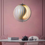 Clérachic Round Metal Pendant Light over a white dining table, slatted globe glowing against a dusty-pink wall.